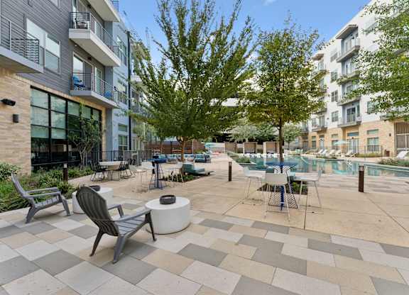 A patio with a table and chairs is surrounded by apartment buildings.