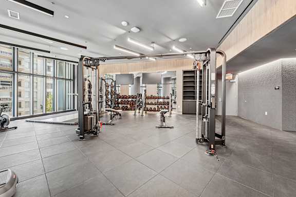 A gym with a variety of equipment including treadmills, weights, and exercise machines.