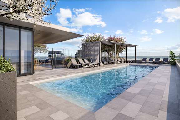 A modern pool area with a clear blue pool and lounge chairs.
