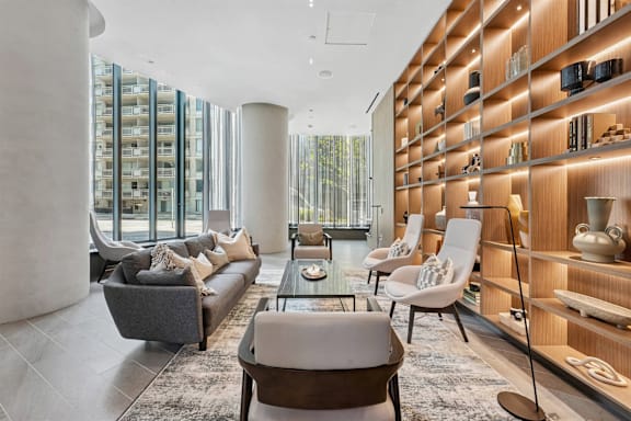 A modern living room with a grey sofa, a coffee table, and a wooden shelf with decorative items.