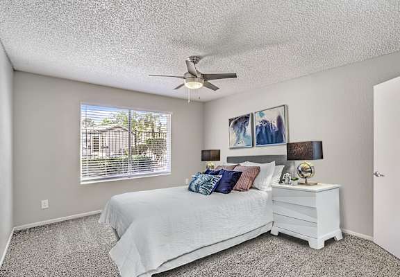 A bedroom with a bed, nightstand, and a ceiling fan.