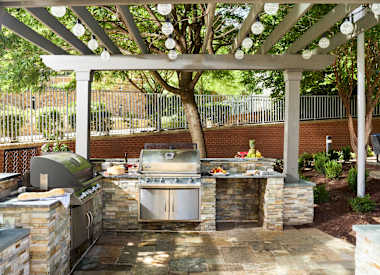 a outdoor kitchen with a grill and a pergola