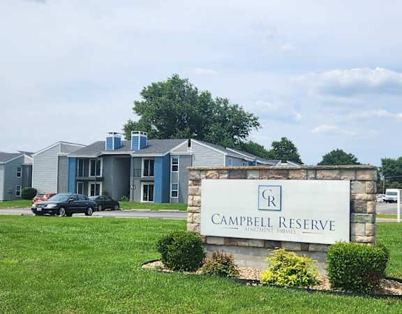 a building with a sign in front of a green field