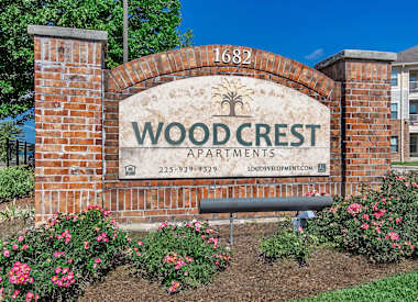 A brick archway with a sign that says Wood Crest Apartments.