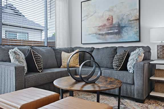 A grey couch with a large abstract painting above it and a coffee table in front. at Avilla Rio Oaks  Apartments, Liberty Hill, TX, 78642