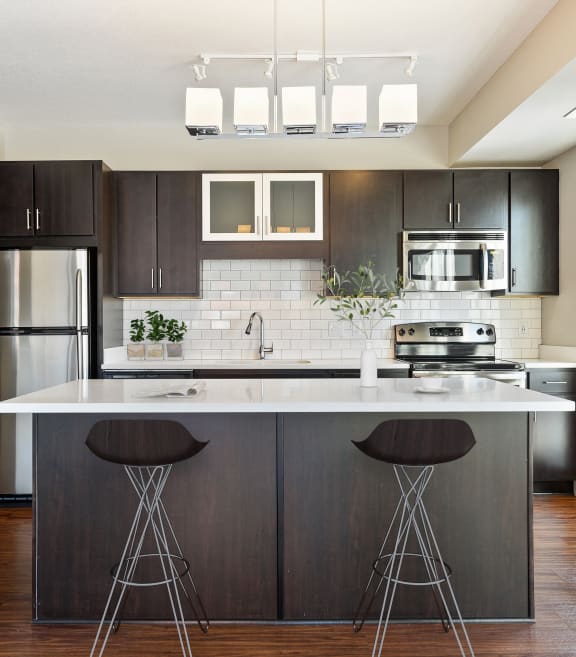 a kitchen with a large island with bar stools and a stainless steel refrigerator at Red 20 Apartments, Minneapolis, MN, 55413