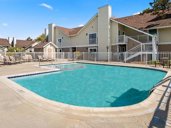 A large swimming pool in front of a building with a white fence around it.