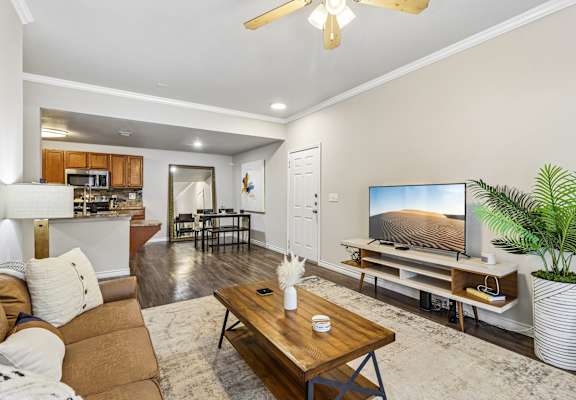 A living room with a brown couch, a wooden coffee table, and a flat screen TV.