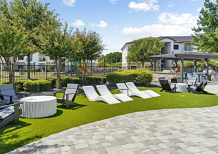 Inviting outdoor lounge space with modern chairs and lush greenery, offering a serene environment for relaxation.