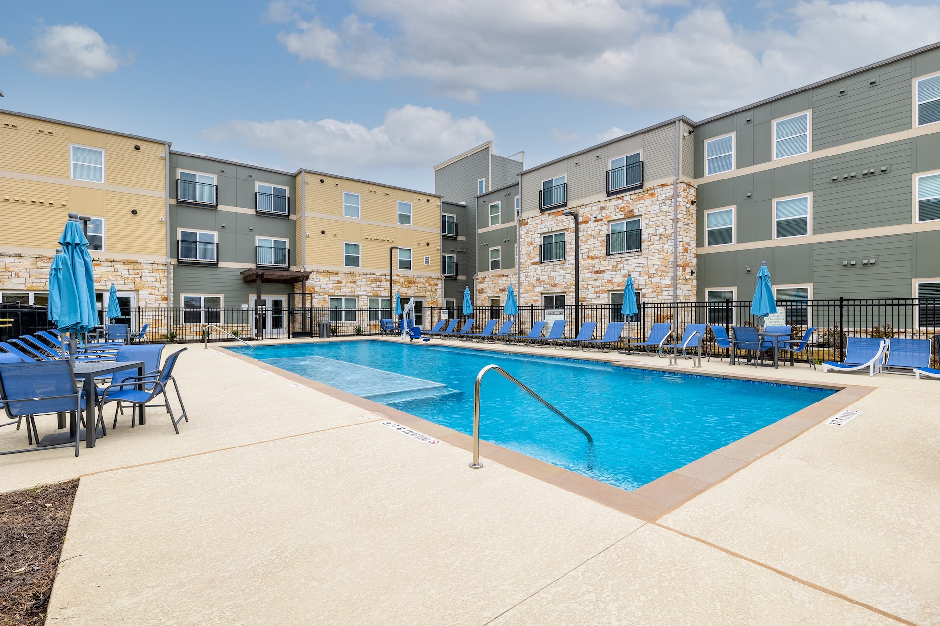 Sparkling outdoor swimming pool and outdoor seating at the Commons at Manor apartment community