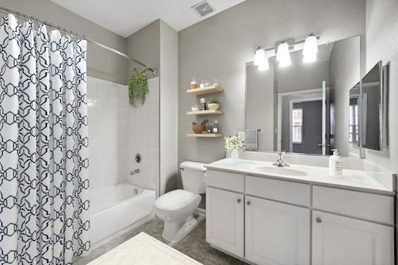 A bathroom with a white toilet, sink, and a shower with a black and white curtain at MetroPlace at Town Center, Maryland