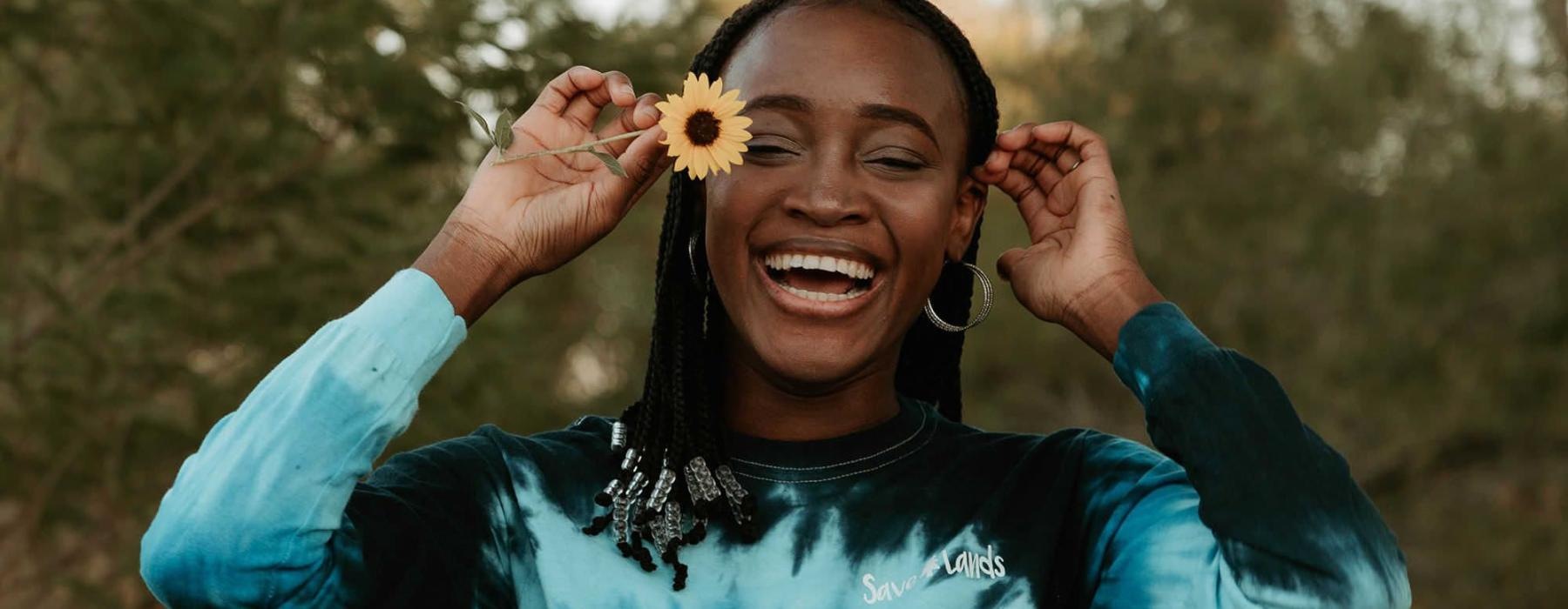 woman holds a flower in her hair in a park