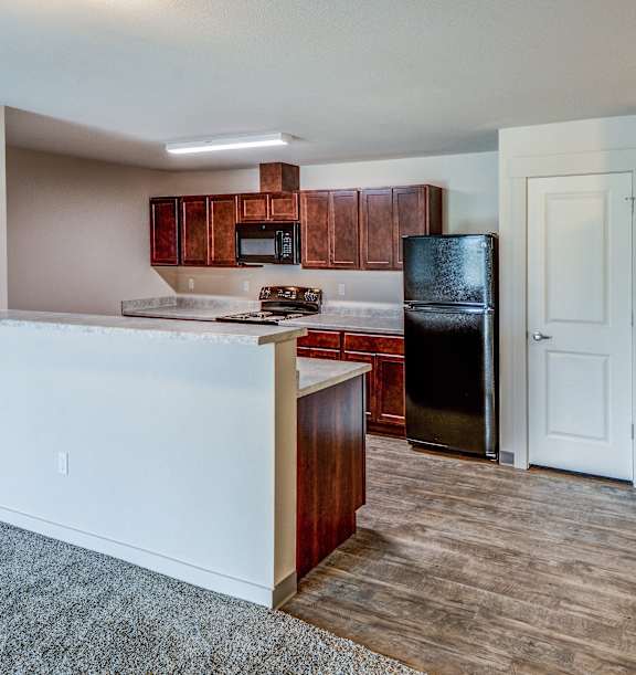 A kitchen with a refrigerator, oven, and microwave.