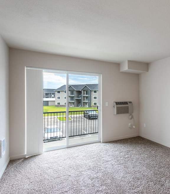 A spacious living room with a view of a residential area through the window.