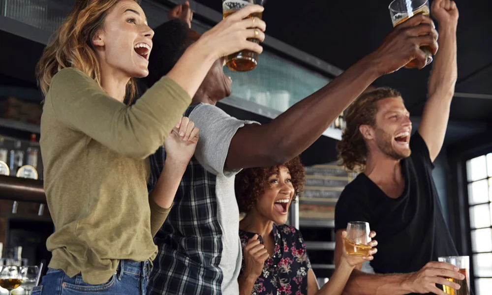 people toasting with drinks in hand at resturant bar