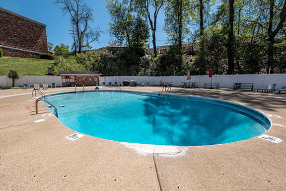 A large outdoor swimming pool with a white fence around it.