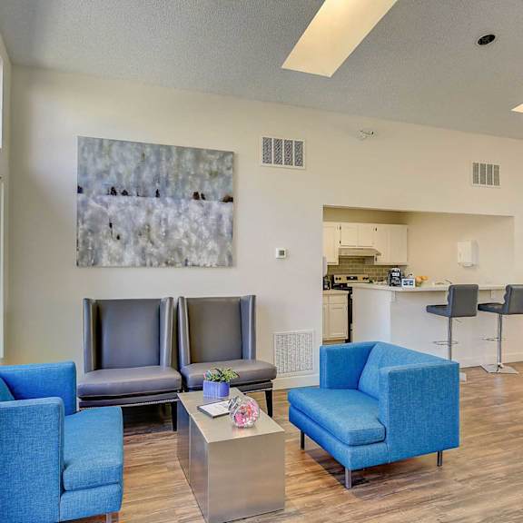 A living room with blue chairs and a grey sofa.