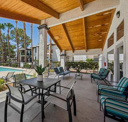 A patio with a table and chairs overlooking a pool.