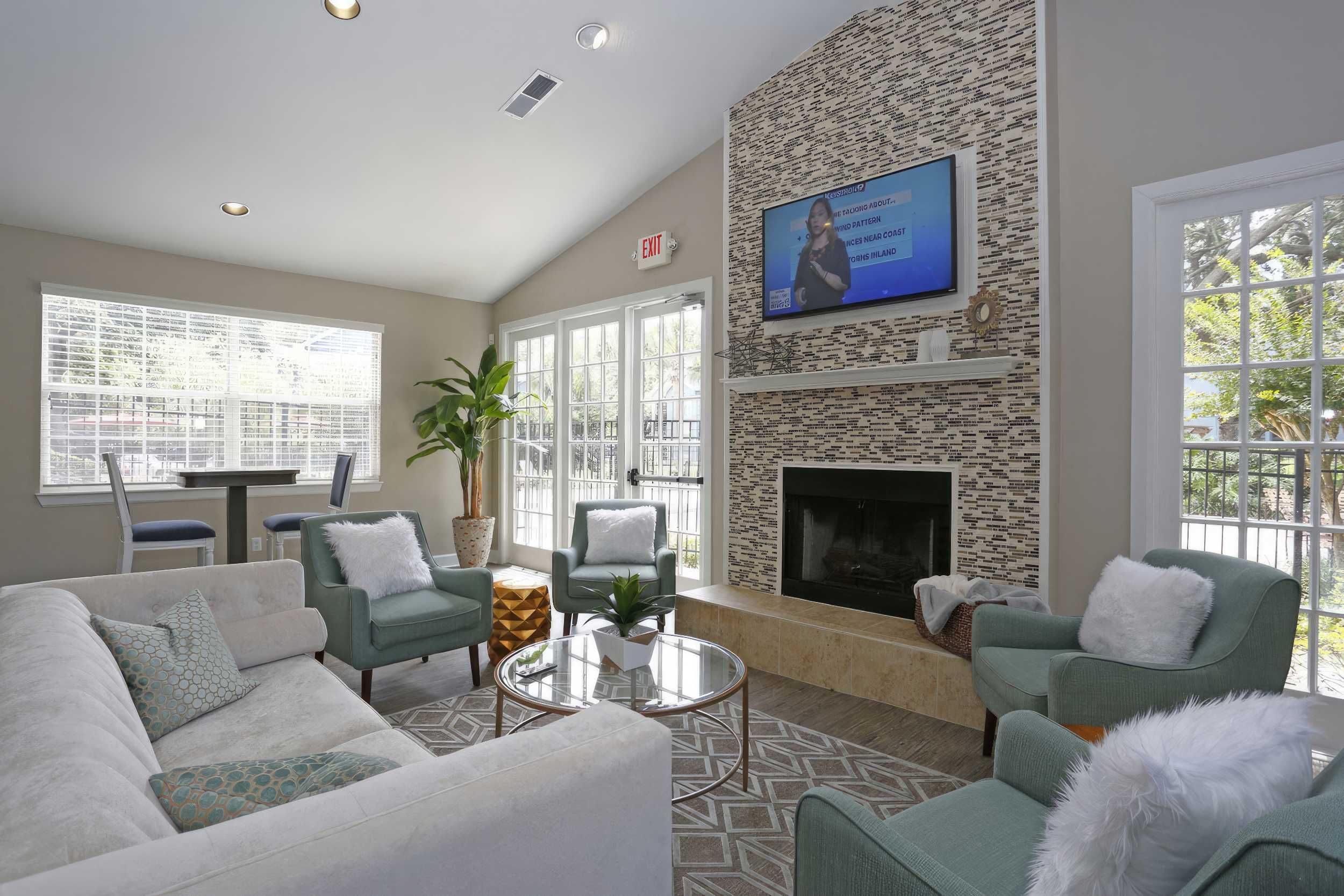 A cozy living area with a fireplace, TV, and seating, featuring modern decor and natural light.