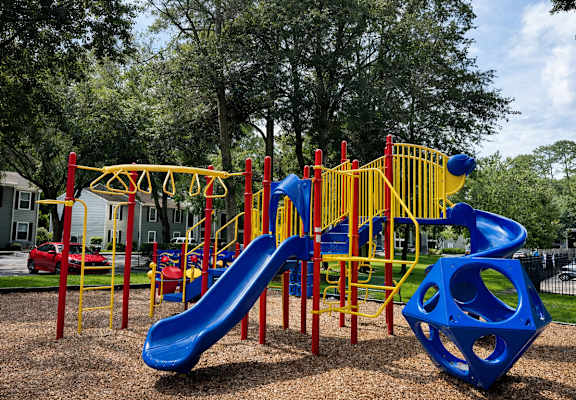 A playground with a blue slide and yellow and red play structures.