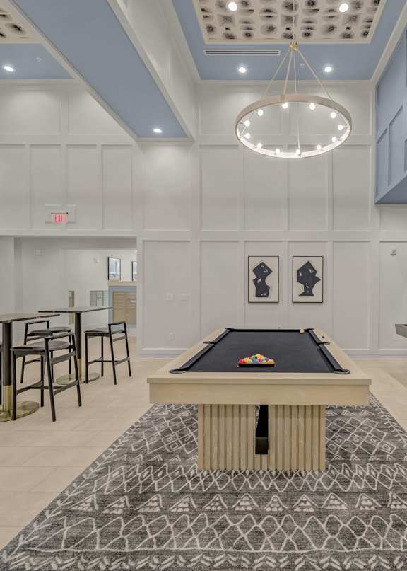 A pool table is in the middle of a room with a bench and chairs.