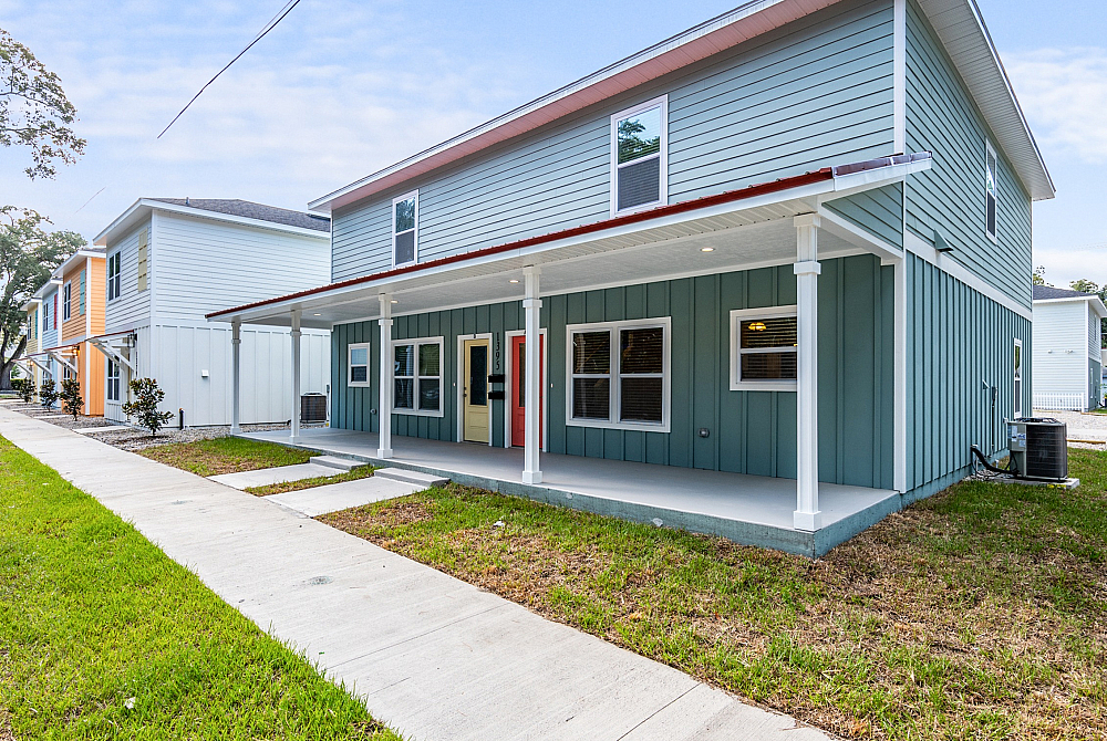 Charming modern townhouse with a covered front porch and vibrant exterior, nestled in a serene neighborhood.