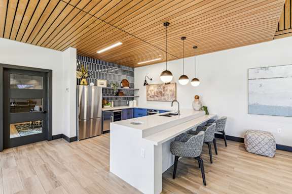 A kitchen with a white island and grey chairs at The Arboretum Apartments, New York 11738
