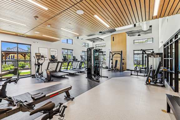A gym with a variety of equipment including treadmills, weights, and exercise machines at The Arboretum Apartments, Farmingville, NY