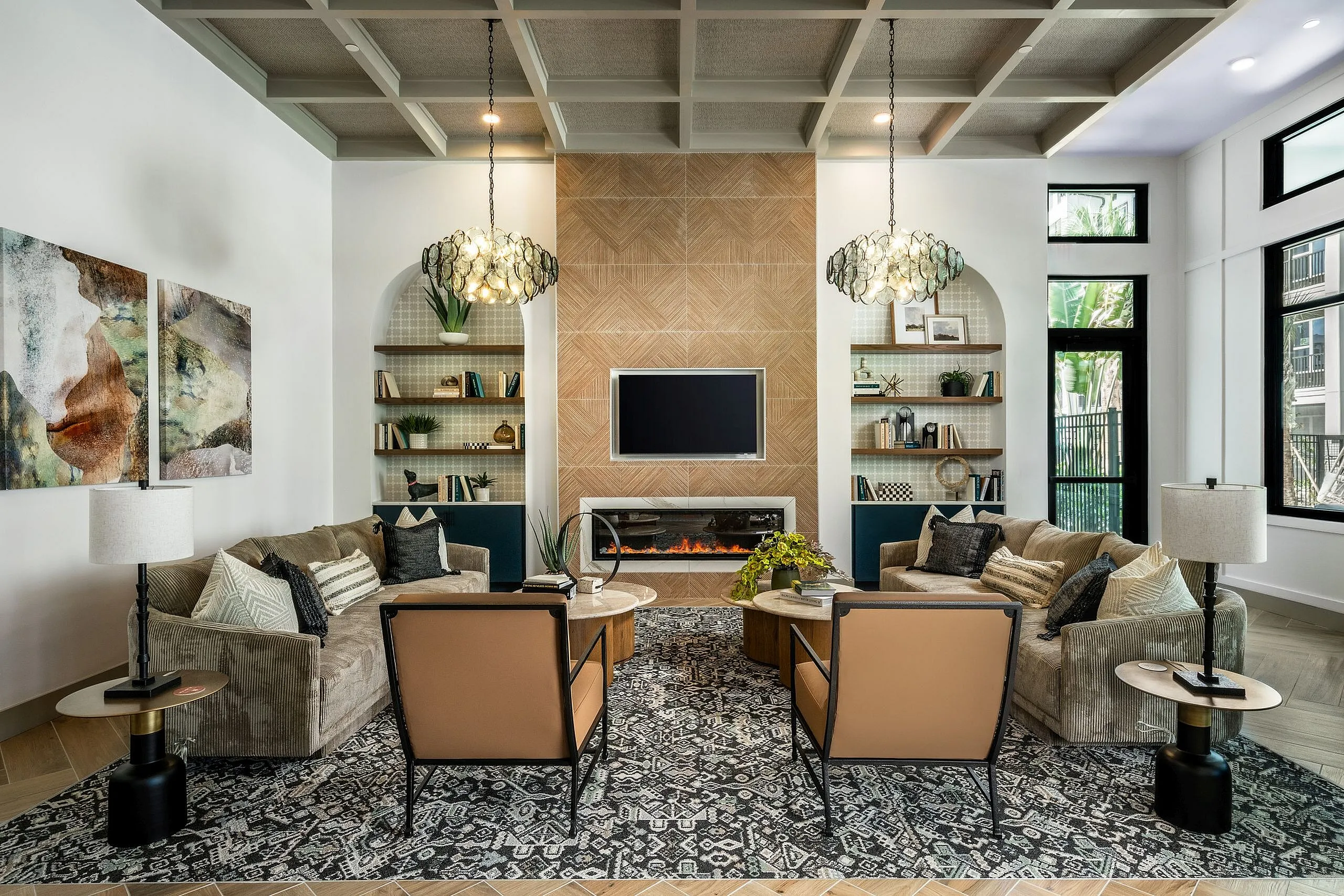 Elegant living room with a modern design, featuring plush sofas, stylish armchairs, and a cozy fireplace, enhanced by chic pendant lighting and large windows for natural light.