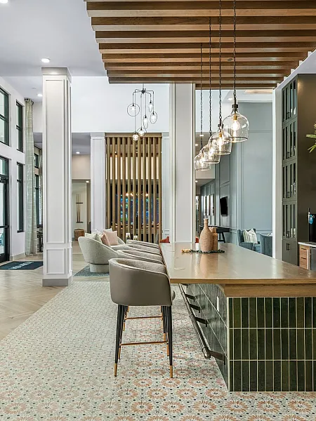 Elegant community lounge featuring modern decor, high ceilings, and abundant natural light with a stylish bar area and cozy seating.