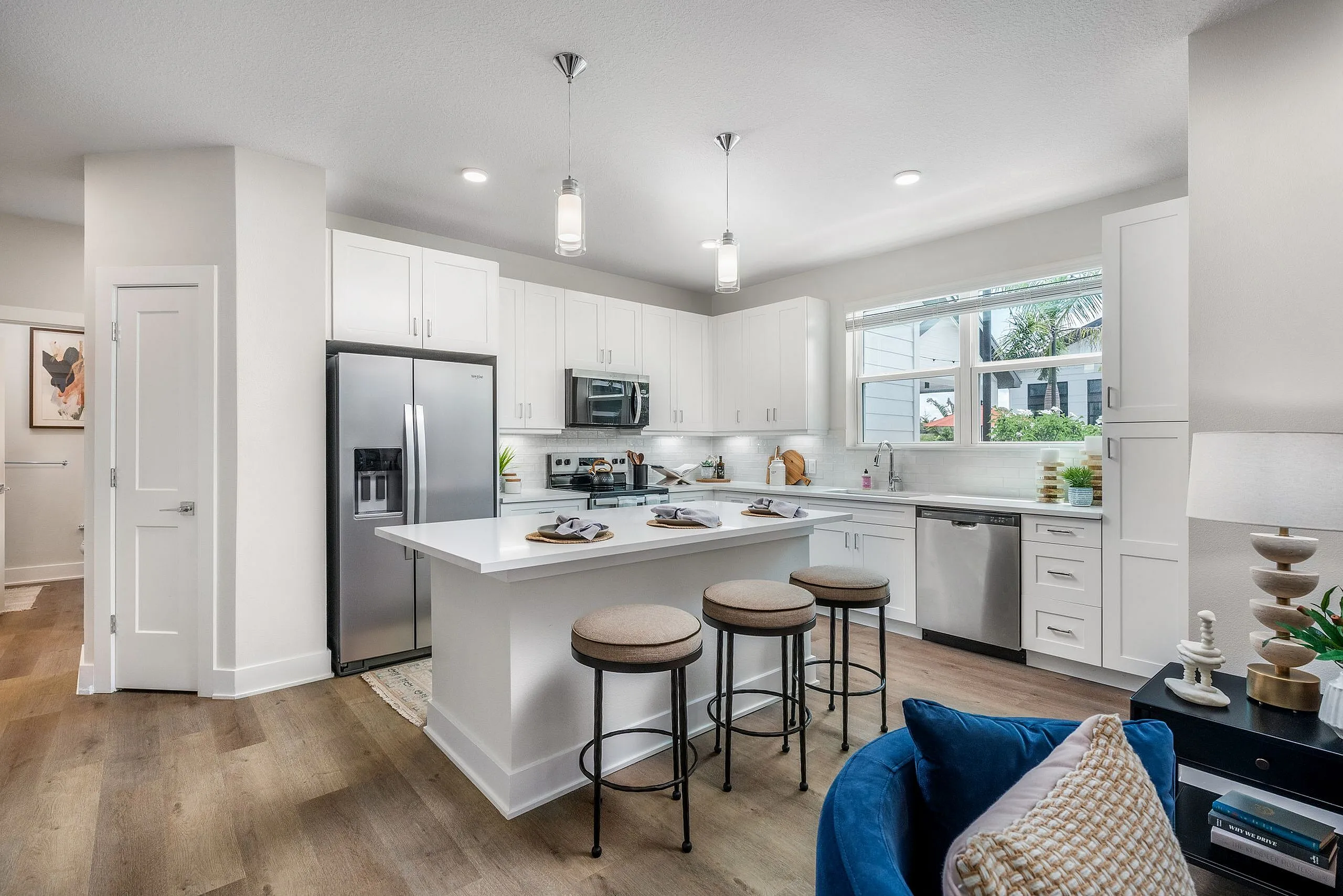 Modern kitchen with sleek white cabinetry, stainless steel appliances, and a cozy breakfast bar with chic stools.