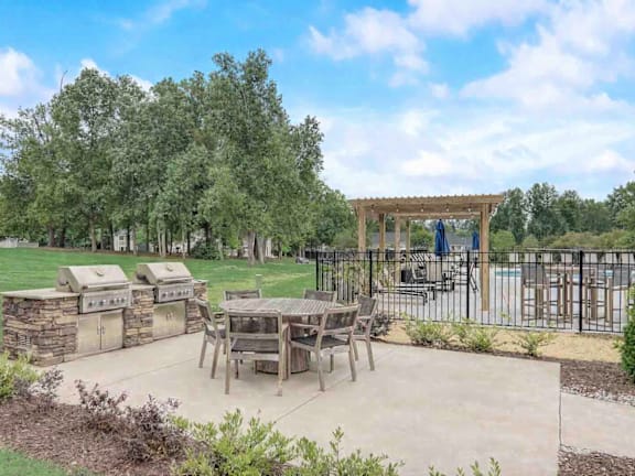 A backyard with a table and chairs and a grill.