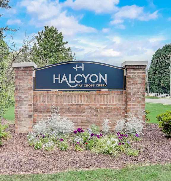 A sign that says Halcyon is surrounded by flowers and shrubs.