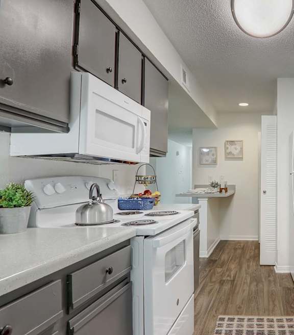A kitchen with white appliances and grey cabinets.