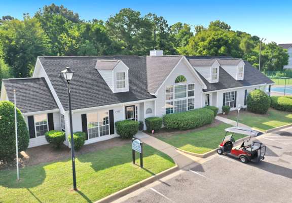 A white house with a grey roof and a red golf cart parked in front.