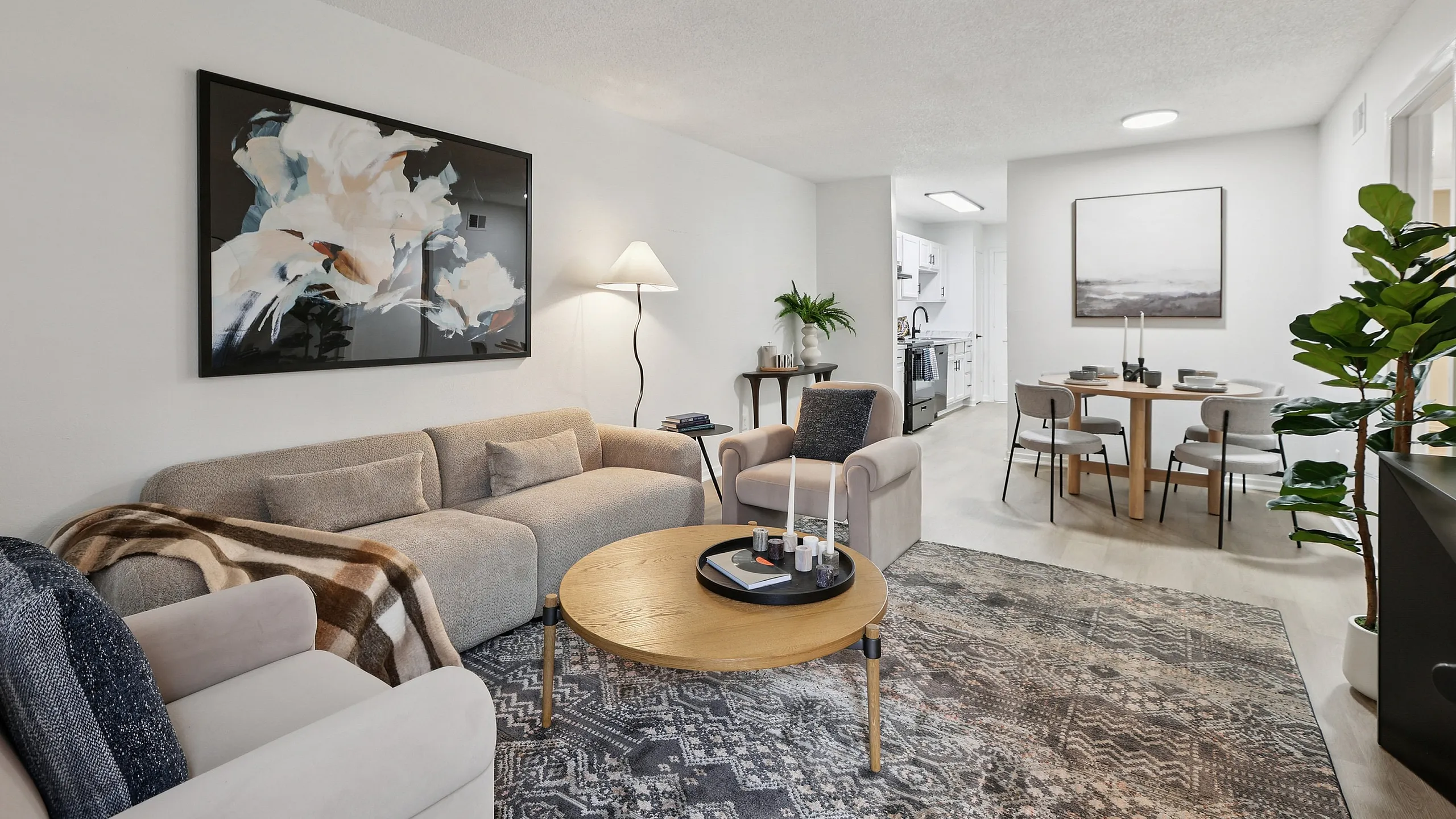 Elegant living room with cozy beige sofa, stylish art, and a charming dining area opening to a modern kitchen.