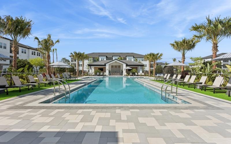 a swimming pool with palm trees and a building in the background