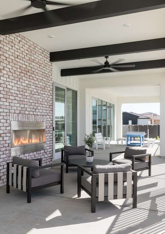 A patio with a fireplace and chairs.