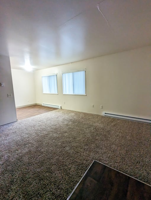 Image from apartment door looking into living room and showing dining area and windows with coverings.