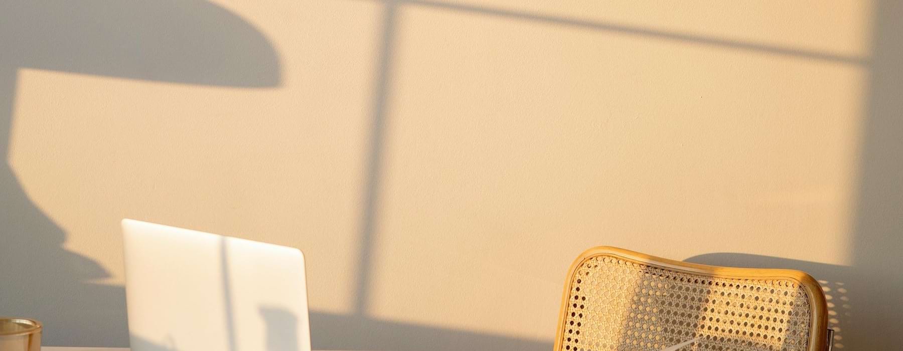 A laptop on a table with a rattan chair at Maret Cove.