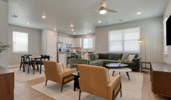 Altura spacious living room with furniture that includes couch and love seats in an open layout that connects to the kitchen.
