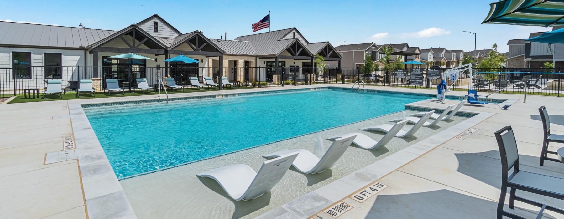Resort style pool with in pool loungers and clubhouse in the background