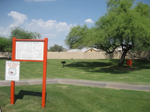 a sign in a park next to a tree