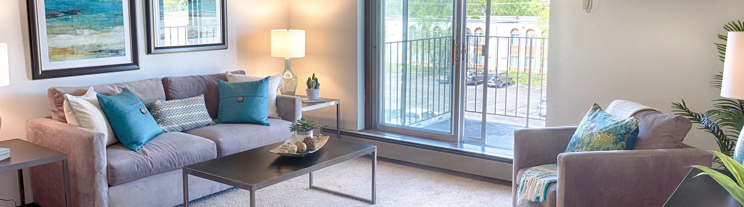 Bright and inviting living room with modern decor, plush seating, and a large sliding door leading to a balcony with a scenic view.