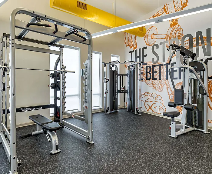 Modern apartment gym featuring state-of-the-art fitness equipment and motivational wall art.