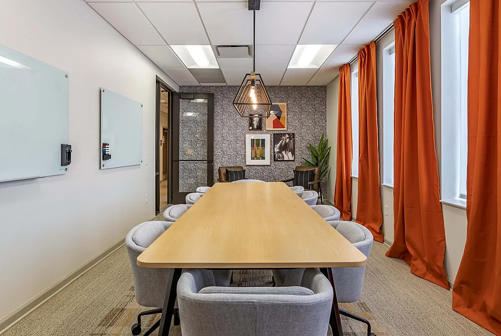 Elegant conference room with modern lighting, stylish decor, and vibrant orange curtains.