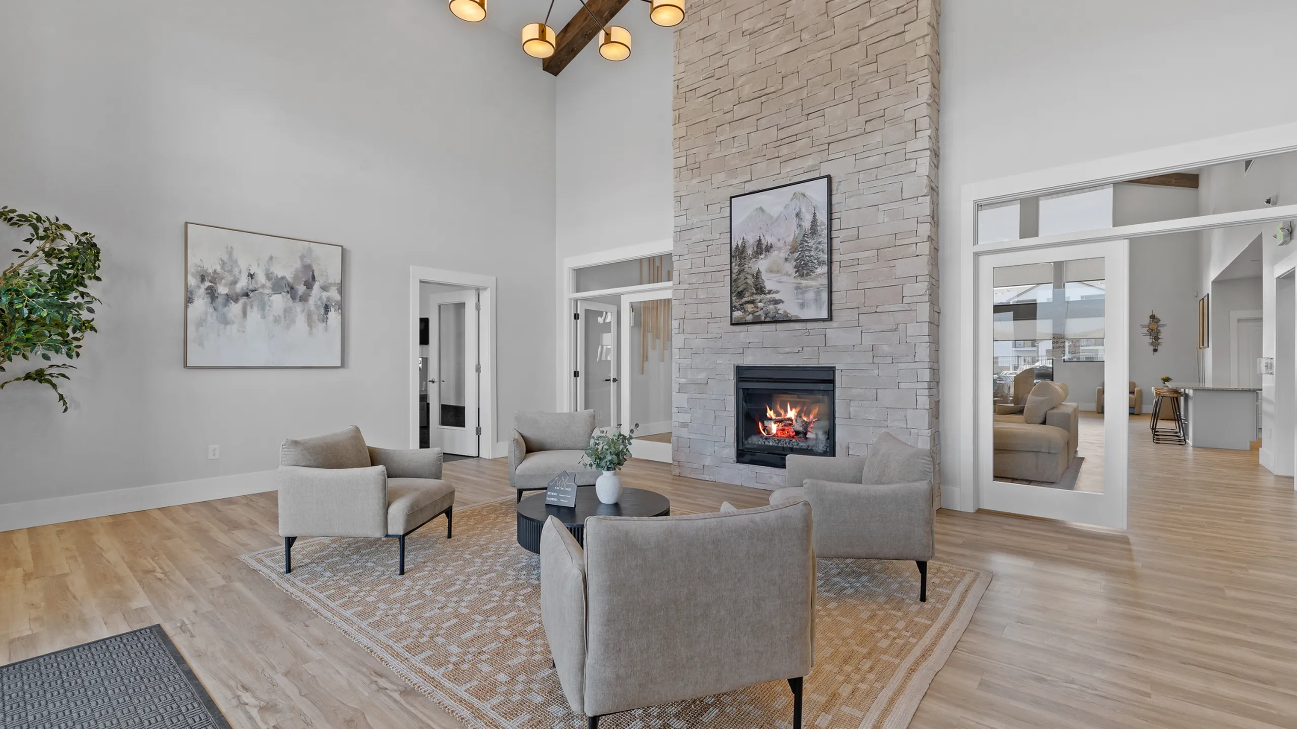 Elegant living room with high ceilings, stone fireplace, and modern decor complemented by cozy seating, creating a warm, inviting ambiance.
