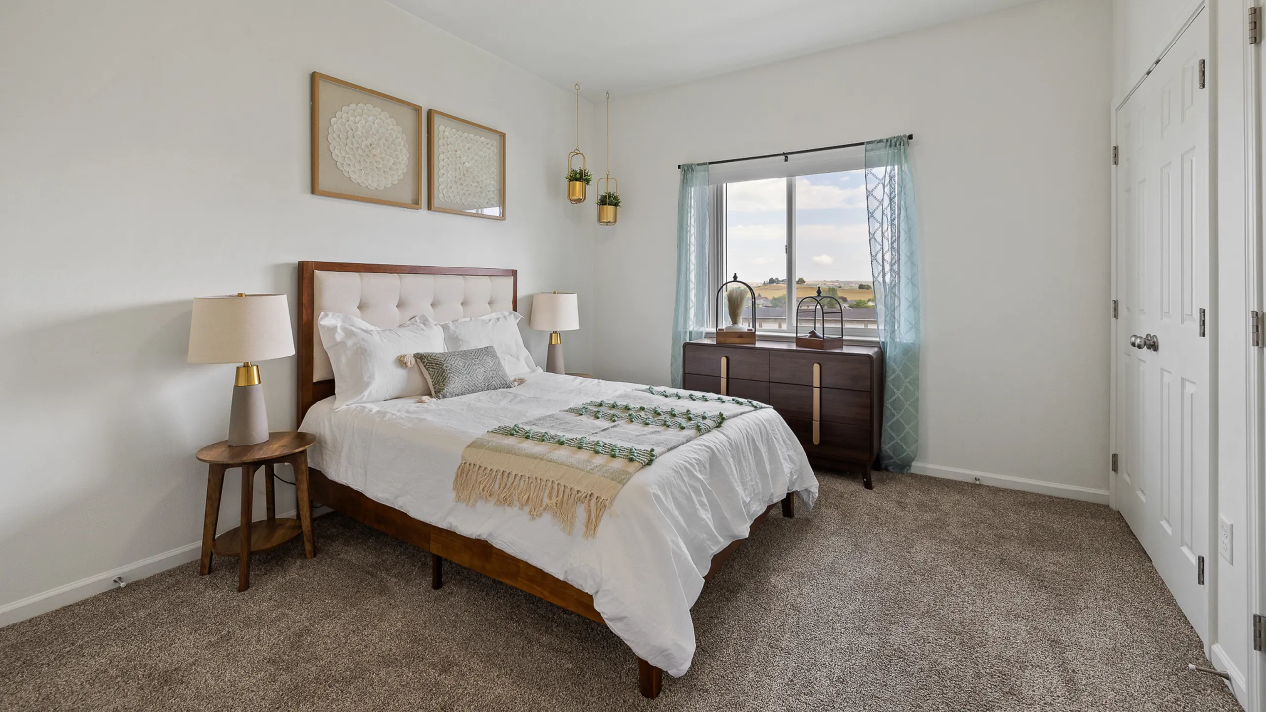 Bright and inviting bedroom with plush carpeting, modern decor, and a large window offering scenic views.