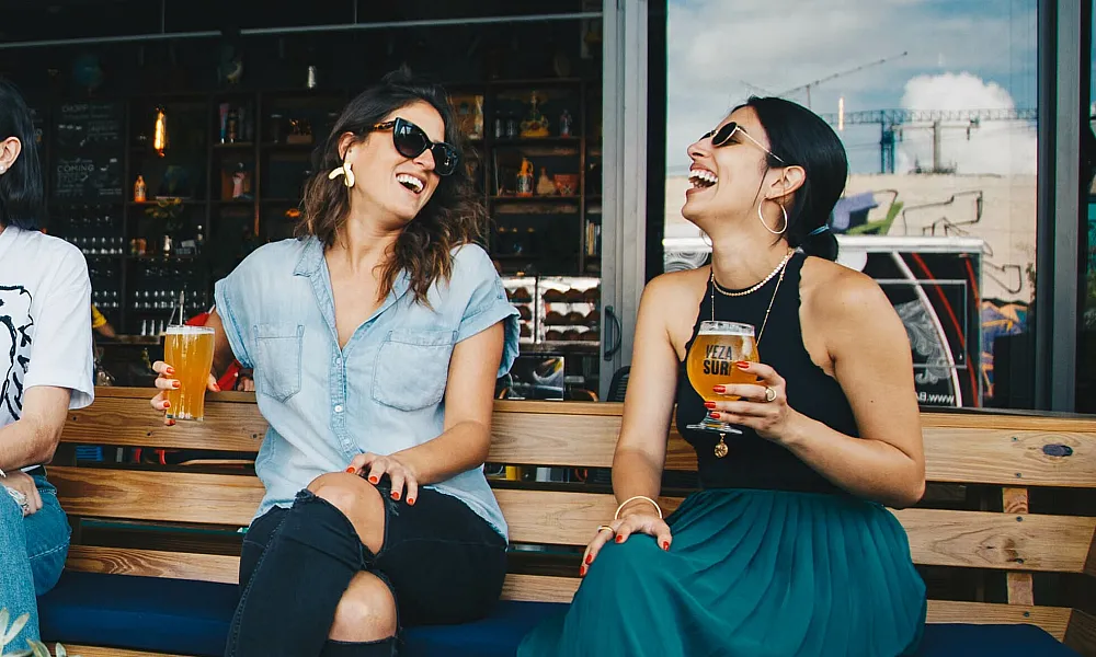 two women drinking beer outside smiling