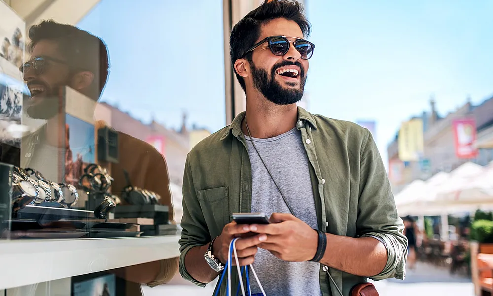 man shopping outdoors holding a phone